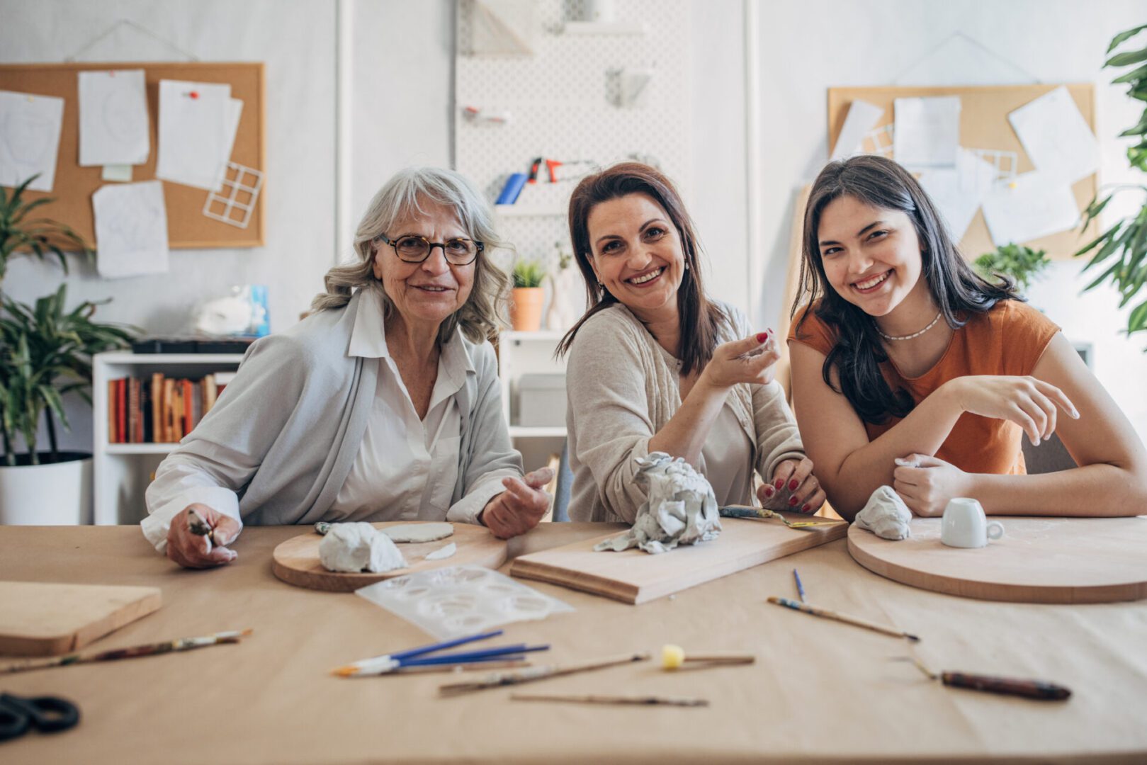 Three women sculpting together at a table.