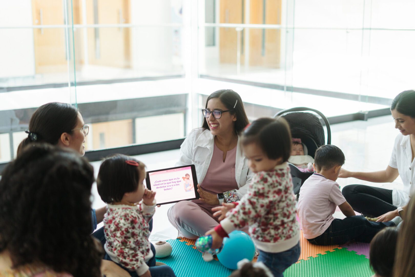 Children and adults sitting on colorful mats.