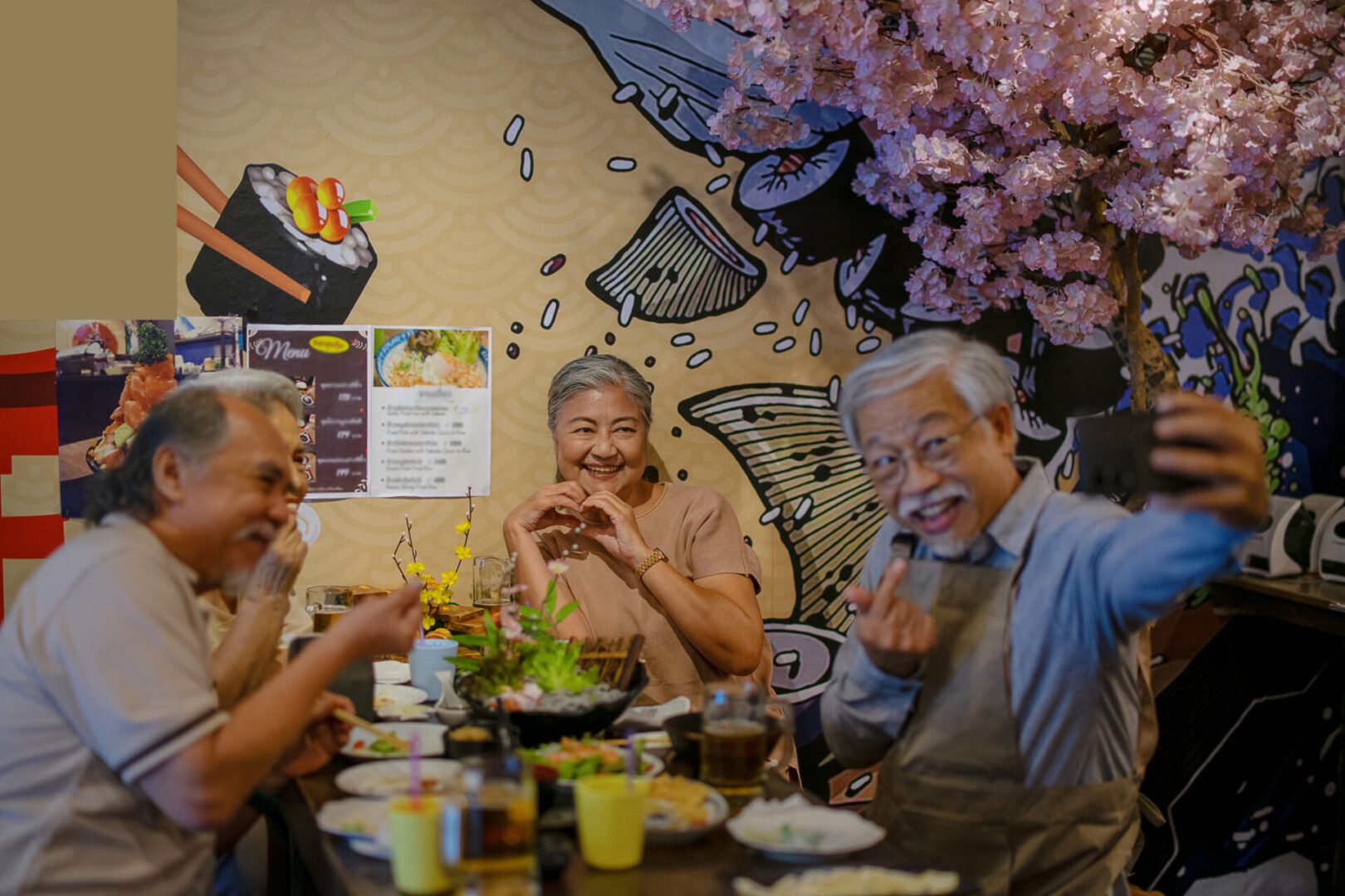 Elderly friends enjoying meal, taking selfie together.