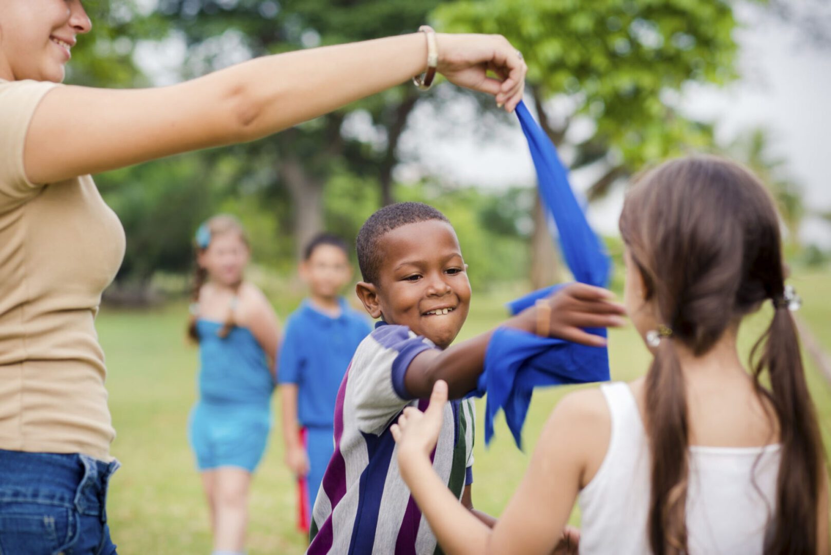 Children playing a game with blue cloth.