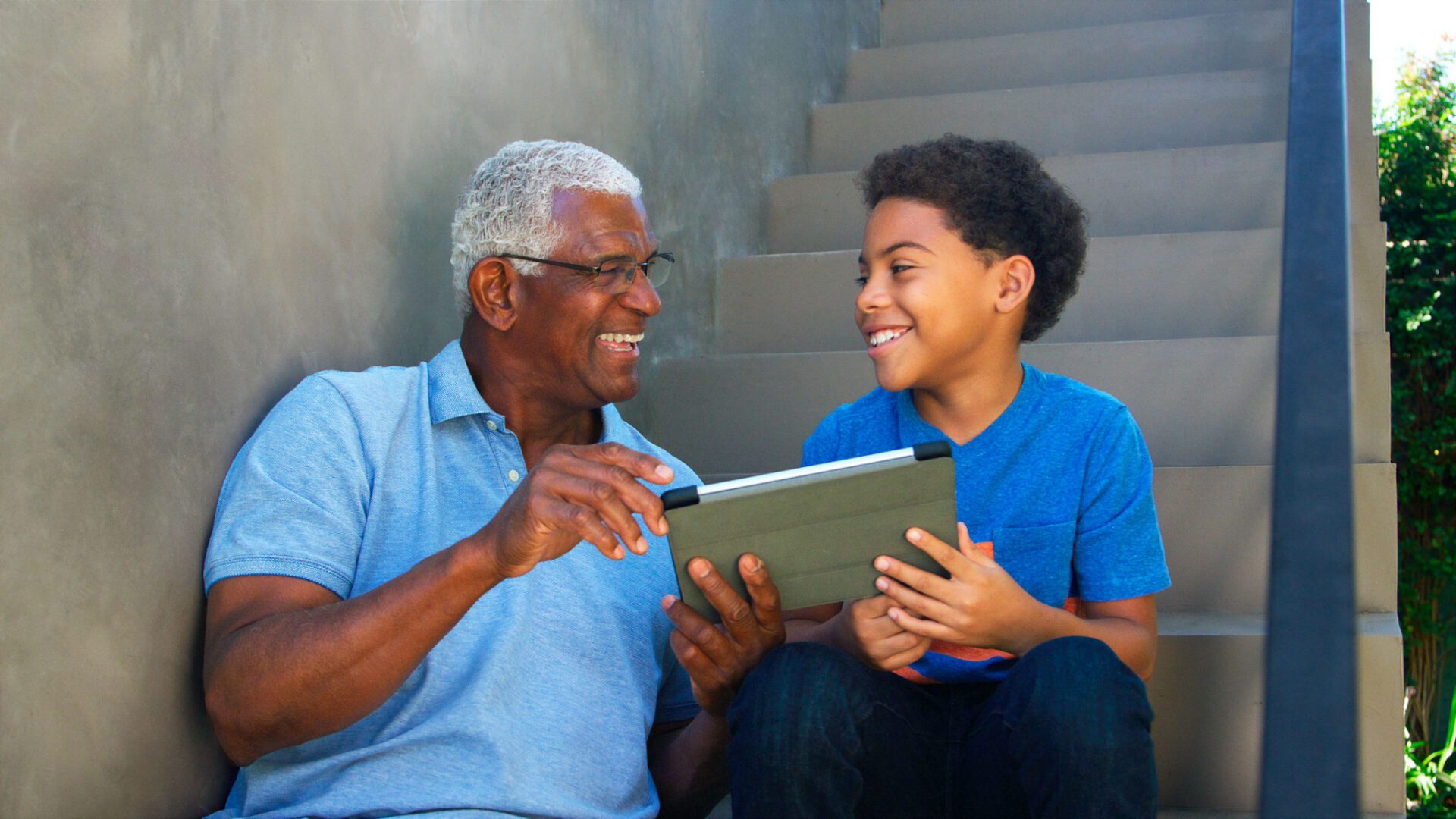 Grandfather and grandson smiling with tablet together.