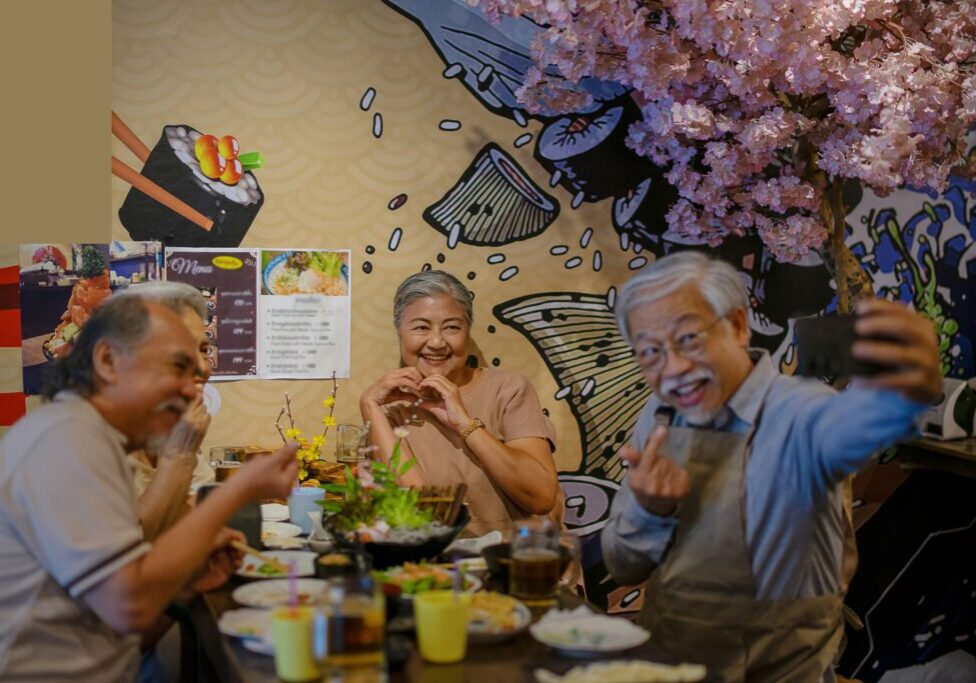 Elderly friends enjoying meal, taking selfie together.